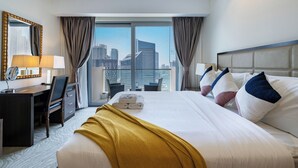 Hotelkamer met een groot bed, een bureau, een stoel en uitzicht op de stadshemel door het raam.