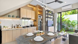 A modern kitchen with wooden cabinets, a built-in microwave, and a dining area with a marble table set for four. - Marea Villa by Kozystay - Jimbaran (Jimbaran)