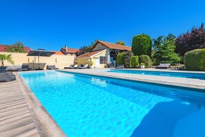 En swimmingpool med liggestole og en bygning i baggrunden.
