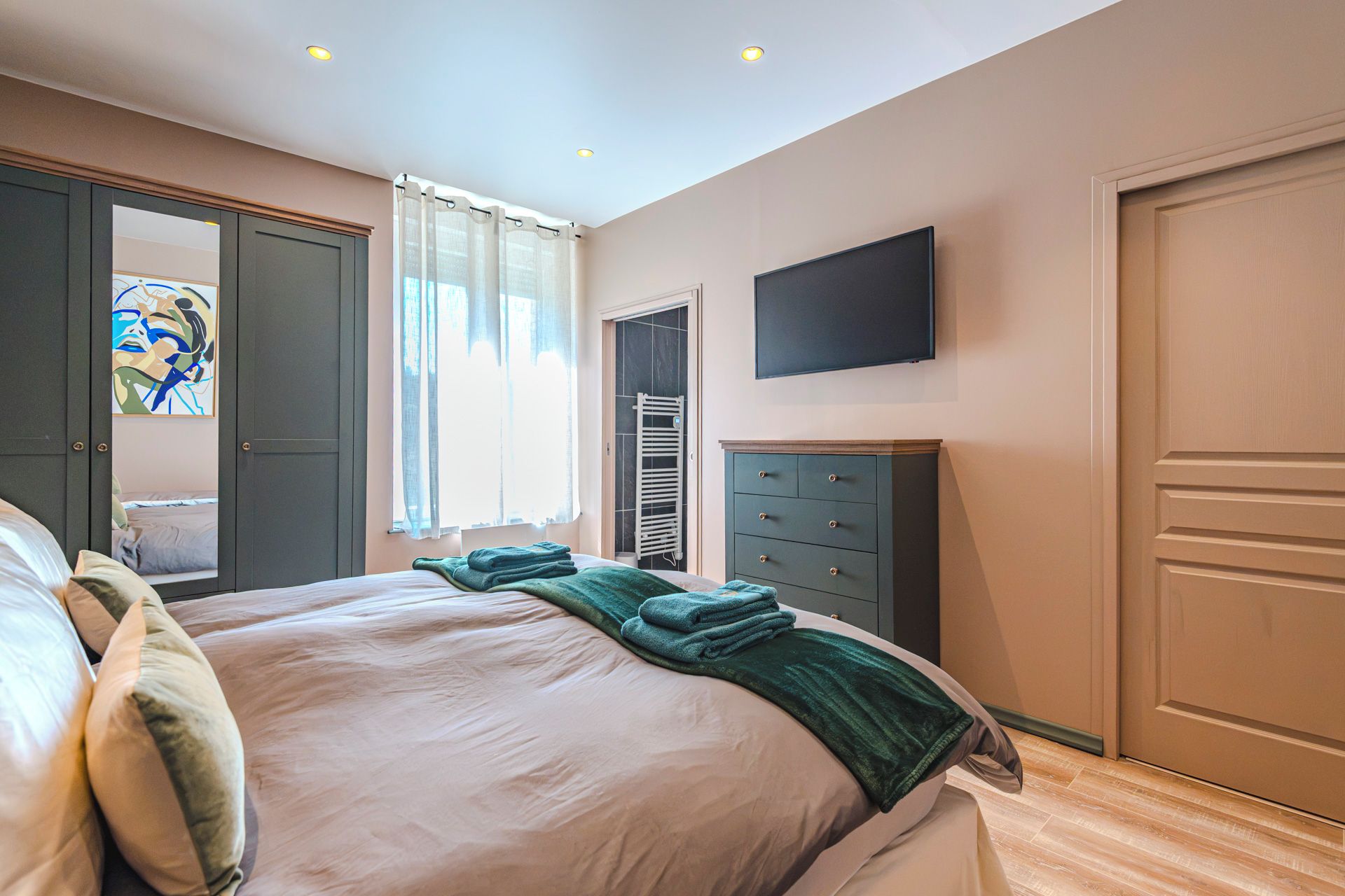 Una camera da letto con un letto, una cassettiera, un televisore e una porta.