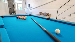 Een pooltafel met ballen en een knuppel, een bank en een trap.