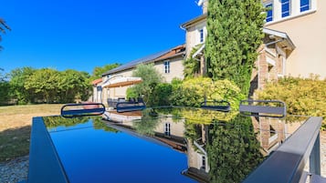 Et hus med swimmingpool, overdækket udendørs siddeområde og en have.
