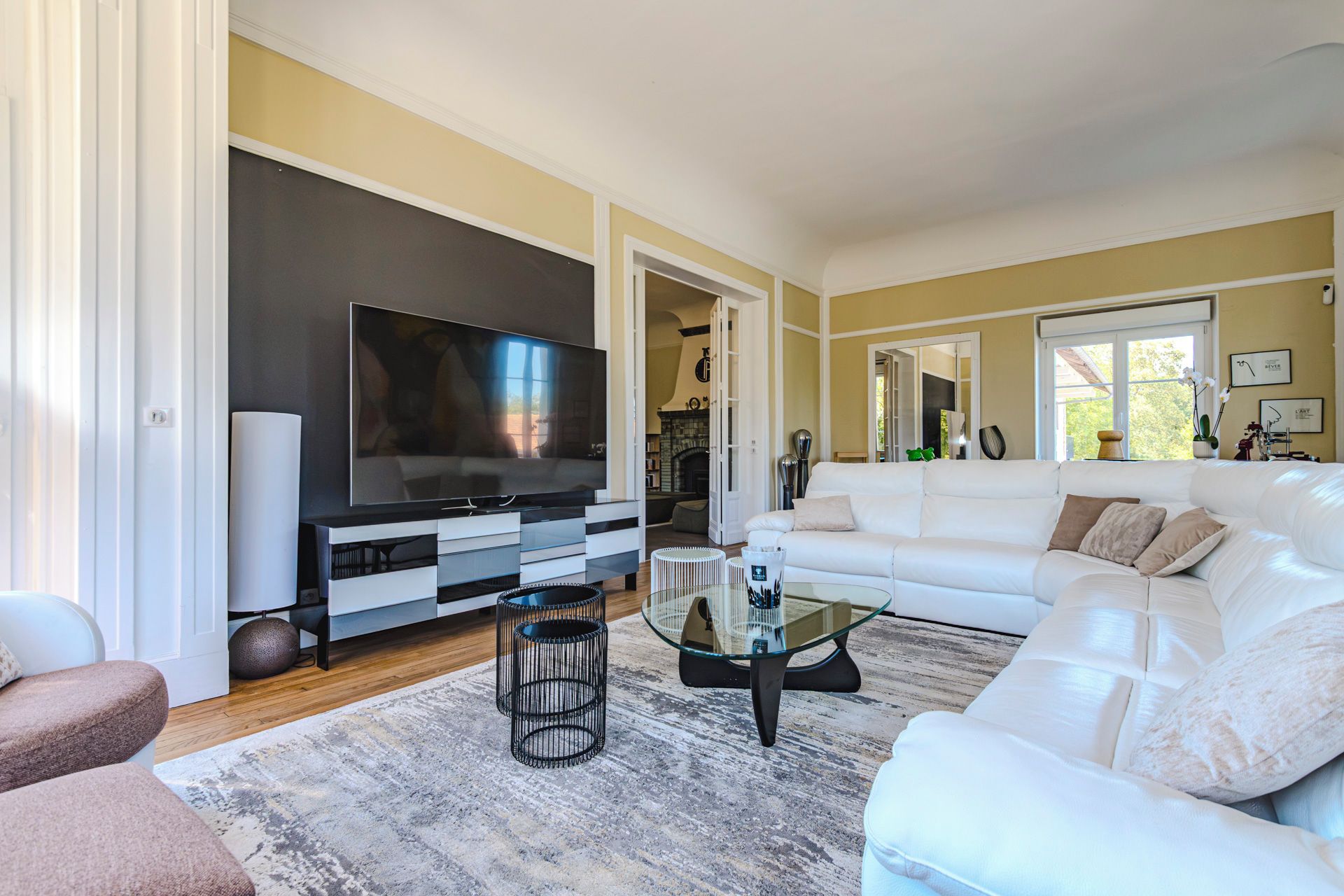 Een moderne woonkamer met een flatscreen televisie, een witte bank en een glazen salontafel.