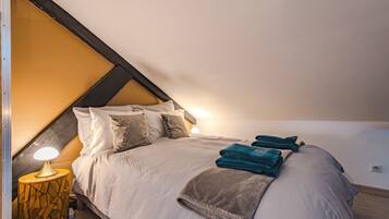 A bedroom with a bed, pillows, a bedside lamp, and folded towels.