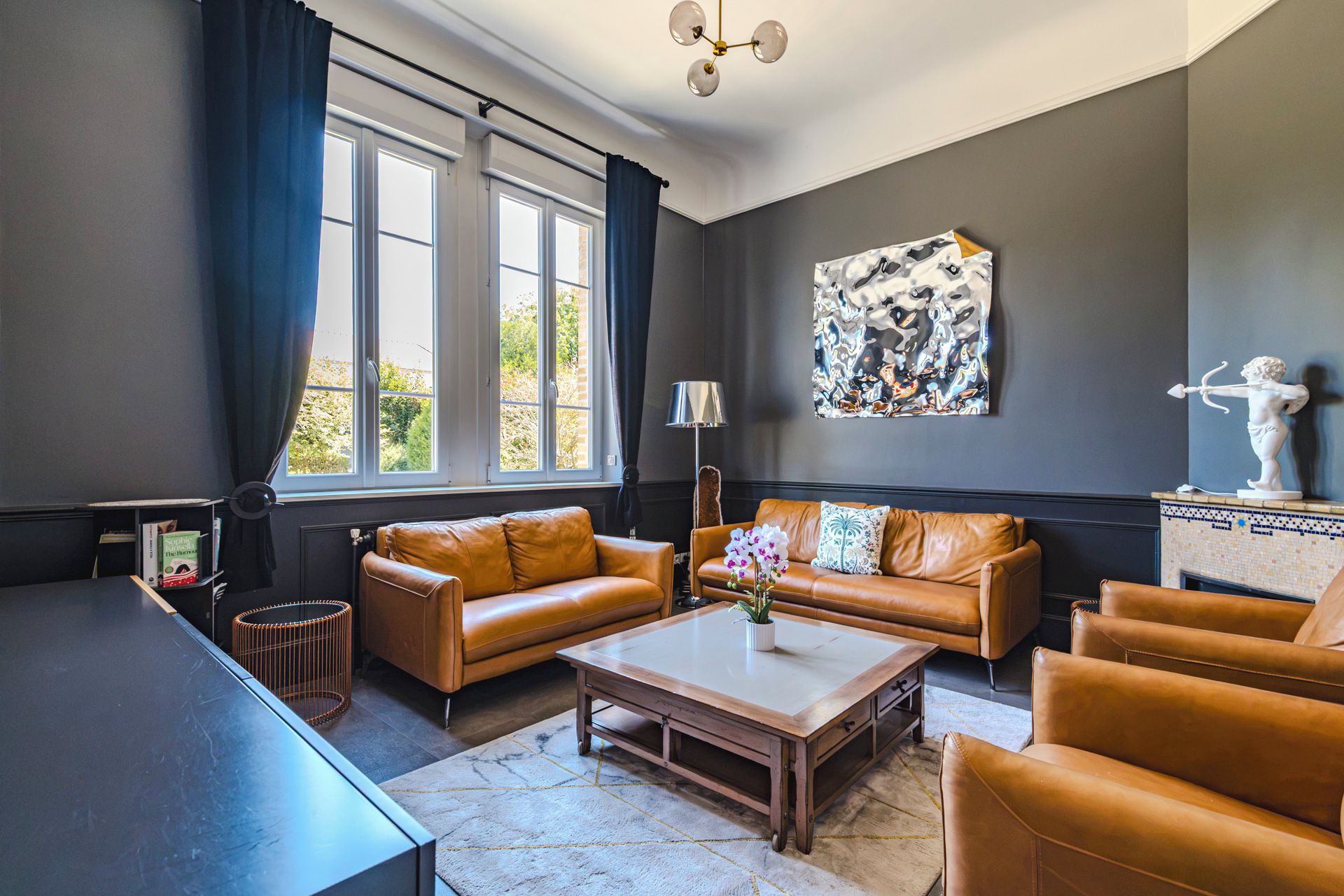 A modern living room with leather sofas, a coffee table, and a large abstract painting on the wall.