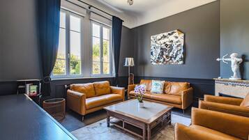 A modern living room with leather sofas, a coffee table, and a large abstract painting on the wall.