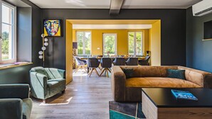 Een moderne woonkamer met een bank, een salontafel, en een eethoek met stoelen en een tafel.