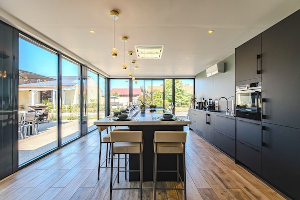Una cocina moderna con una isla grande, taburetes de bar y vistas al exterior.