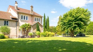 A large house with a well-maintained lawn and a variety of trees and shrubs.