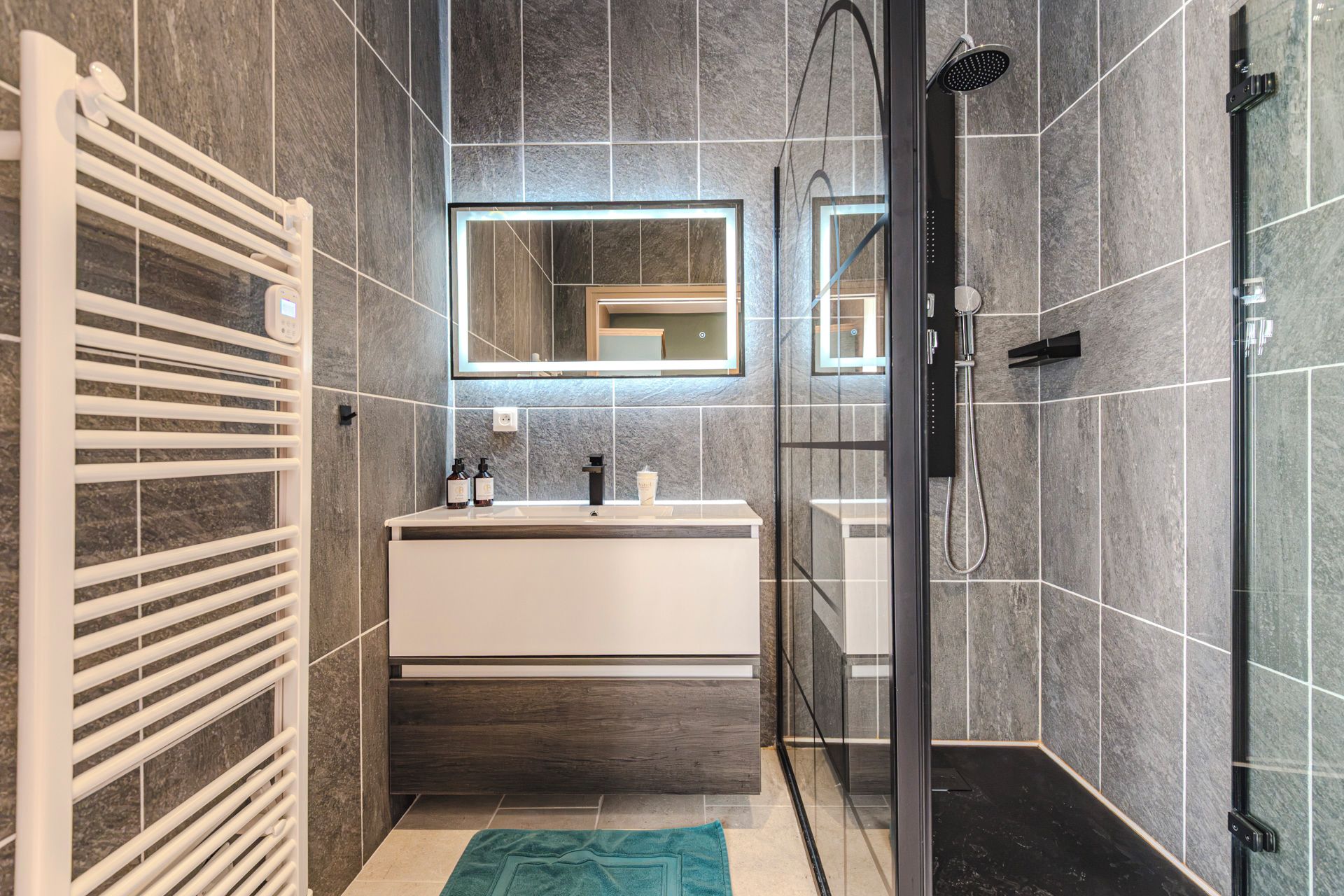 Une salle de bain moderne avec une douche, un meuble-lavabo blanc et un porte-serviettes.