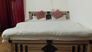 A bed with a wooden headboard, two pillows, and a white bedspread. - Ooncha Dana Home Stay (Uttarakhand)