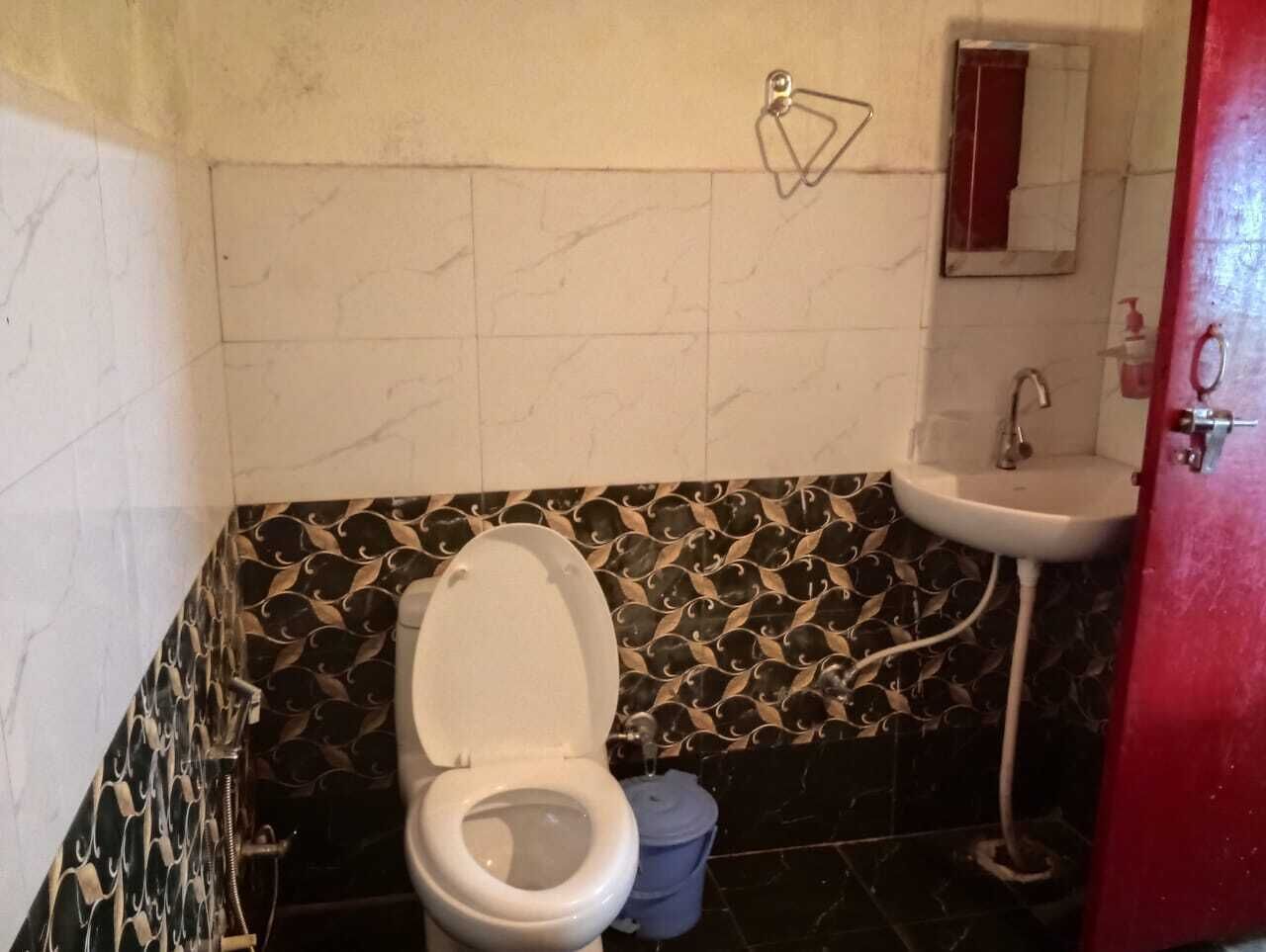 A bathroom with a toilet, sink, and mirror.