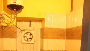 A small bathroom with a toilet, a bidet, and a water heater. - Ooncha Dana Home Stay (Uttarakhand)