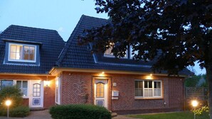 Ein zweigeschossiges Backsteinhaus mit gepflasterter Auffahrt und einem gepflegten Rasen.