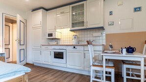 Eine moderne Küche mit weißen Schränken, einem Holzespeisetisch und einem eingebauten Backofen.