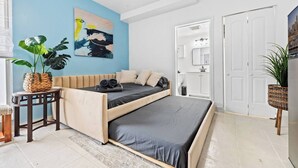 Une chambre à coucher moderne avec un lit, une table de chevet, une plante en pot et un tableau au mur.