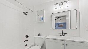 Une salle de bain moderne équipée d’une baignoire, de toilettes, d’un lavabo et d’un miroir.