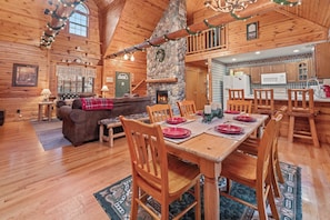 Interior acogedor de una cabaña de madera con comedor, chimenea y cocina.