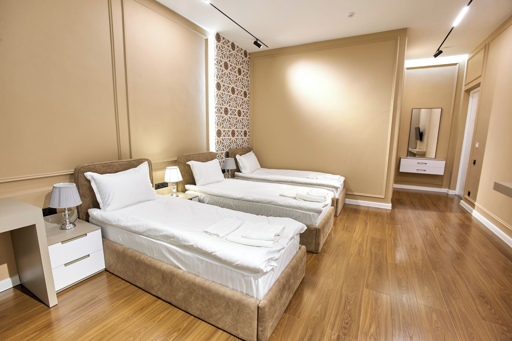 Une chambre d’hôtel avec deux lits, une table de chevet, une lampe et un miroir.