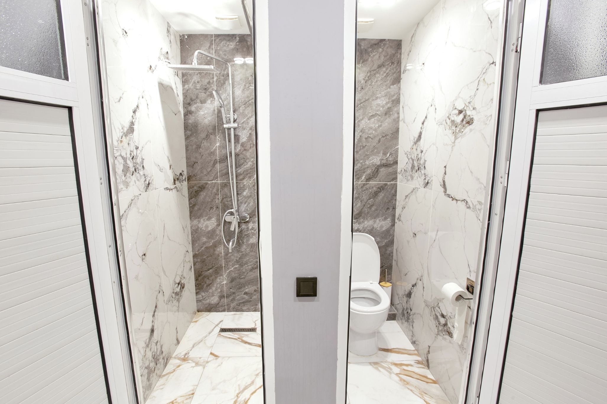 Un baño con ducha, inodoro y suelo de mármol.