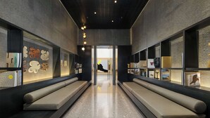 Un hall d’entrée moderne avec un espace salon central, un comptoir d’accueil et une vue sur l’intérieur de l’hôtel.