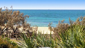 A beach view with a wooden fence, dry shrubs, and a clear blue sky. - Caloundra Retro Beach House in Front of Ocean (Caloundra Region)