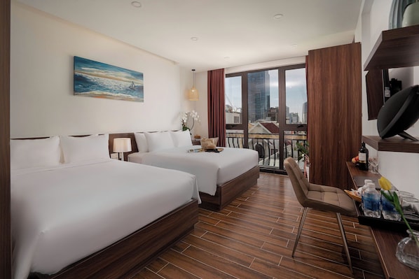 Habitación de hotel con dos camas, un escritorio, una silla, un televisor y un amplio ventanal con vista a la ciudad.