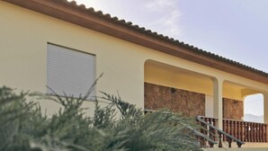 Un bâtiment doté d’un toit en tuiles, d’une façade en pierre et d’un balcon avec une rambarde en métal.