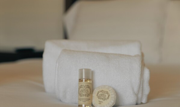 A neatly made bed with a white towel and two toiletries on it. - Casa do Eirado by Alponte Ponte de Lima (Ponte de Lima)
