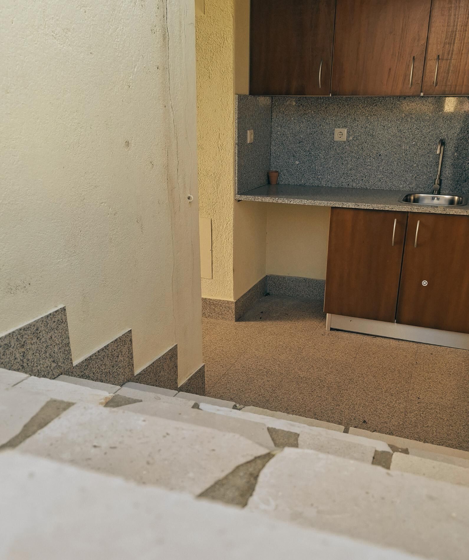 Cucina con piano di lavoro in granito, mobili in legno e lavello in acciaio inossidabile.