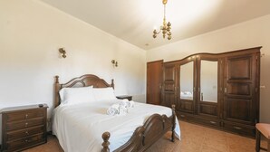 Une chambre à coucher avec un lit en bois, une table de chevet, une commode et une armoire.