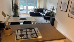 Una cocina moderna con estufa a gas, una mesa de comedor y un sofá de cuero negro al fondo.