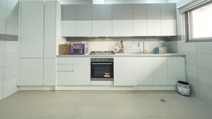 A modern kitchen with white cabinets, a built-in oven, a microwave, and a gas stove.