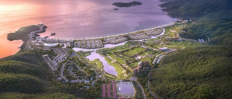 An aerial view of a coastal resort with multiple buildings, golf courses, and a large body of water.