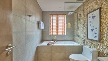 Un baño moderno con bañera, inodoro y ventana con persianas de madera.