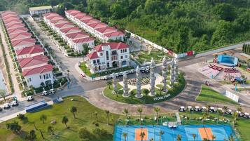 A resort with multiple buildings, a central courtyard with statues, and a sports court.