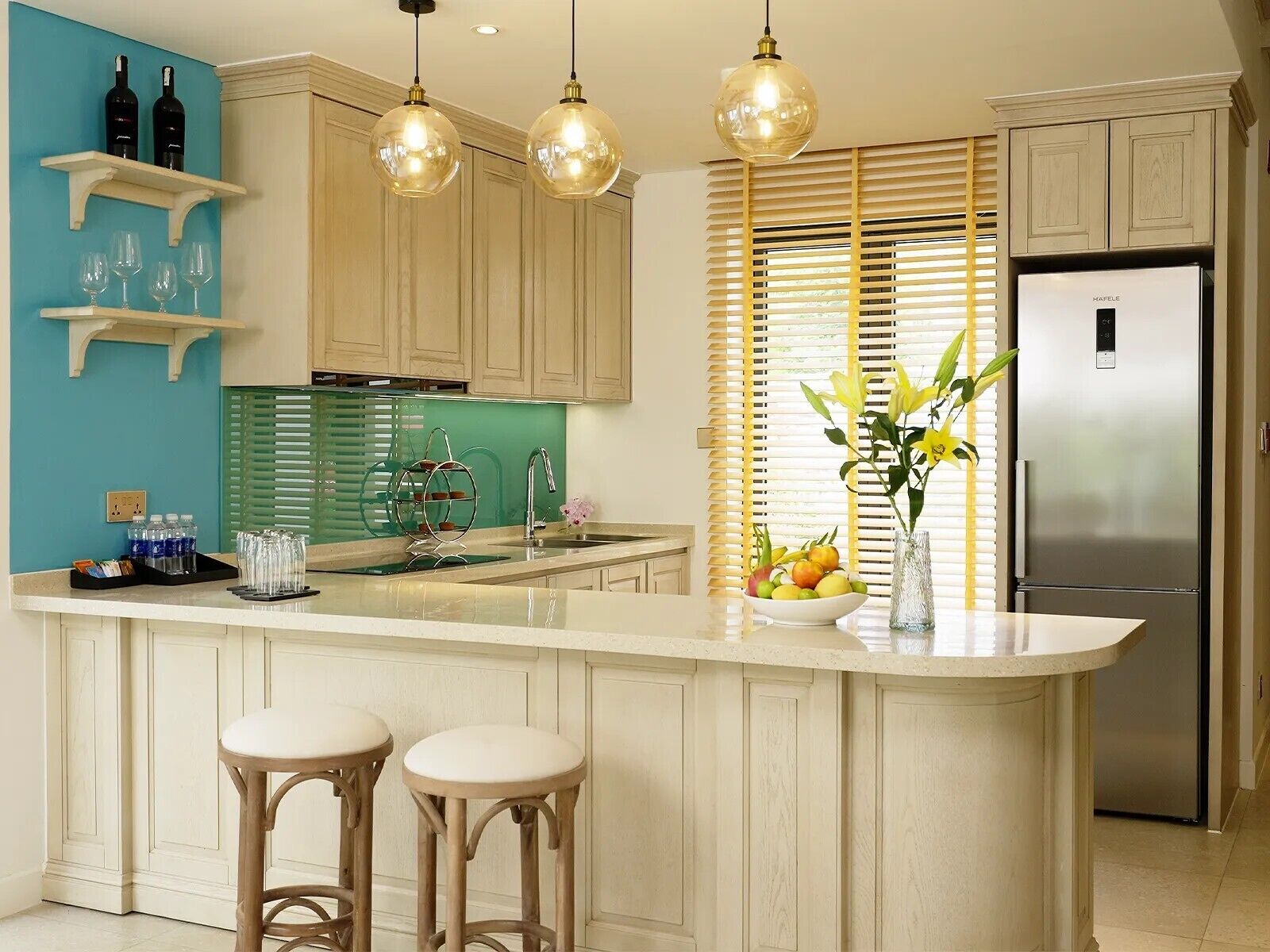 A kitchen with a central island, bar stools, a stainless steel refrigerator, and a window with blinds.