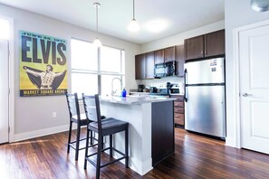 A modern kitchen with a central island, stainless steel appliances, and a poster on the wall.