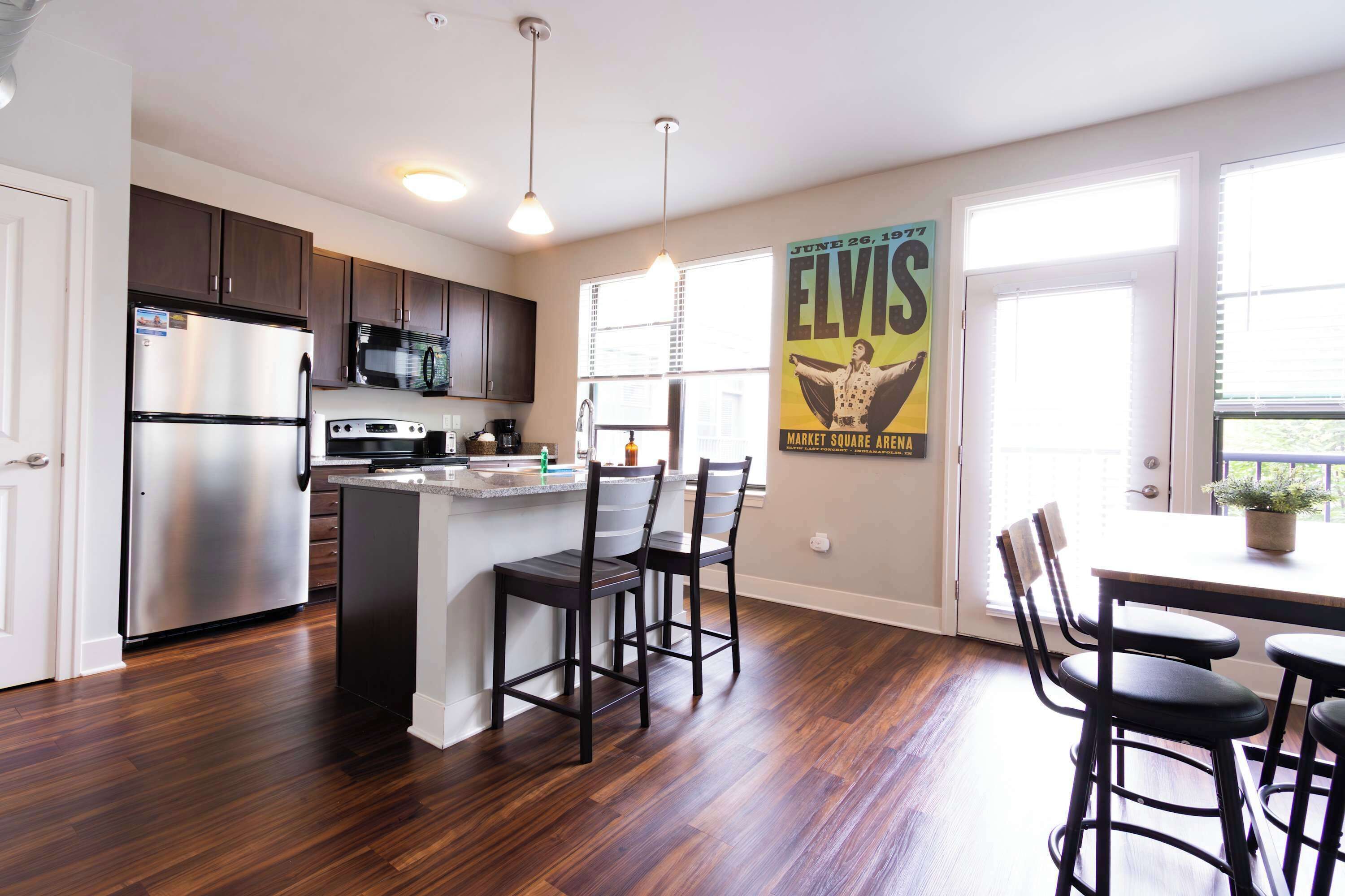 A modern kitchen with stainless steel appliances, a central island, and a dining area with bar stools.