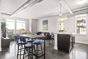 A modern kitchen with a central island, bar stools, and a dining table.