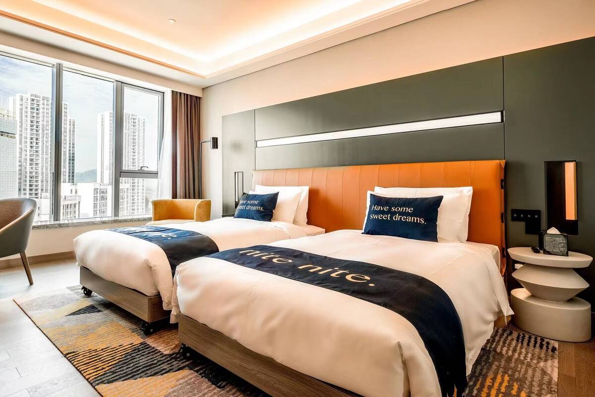 Ein Hotelzimmer mit zwei Betten, einem Schreibtisch und einem Stuhl.
