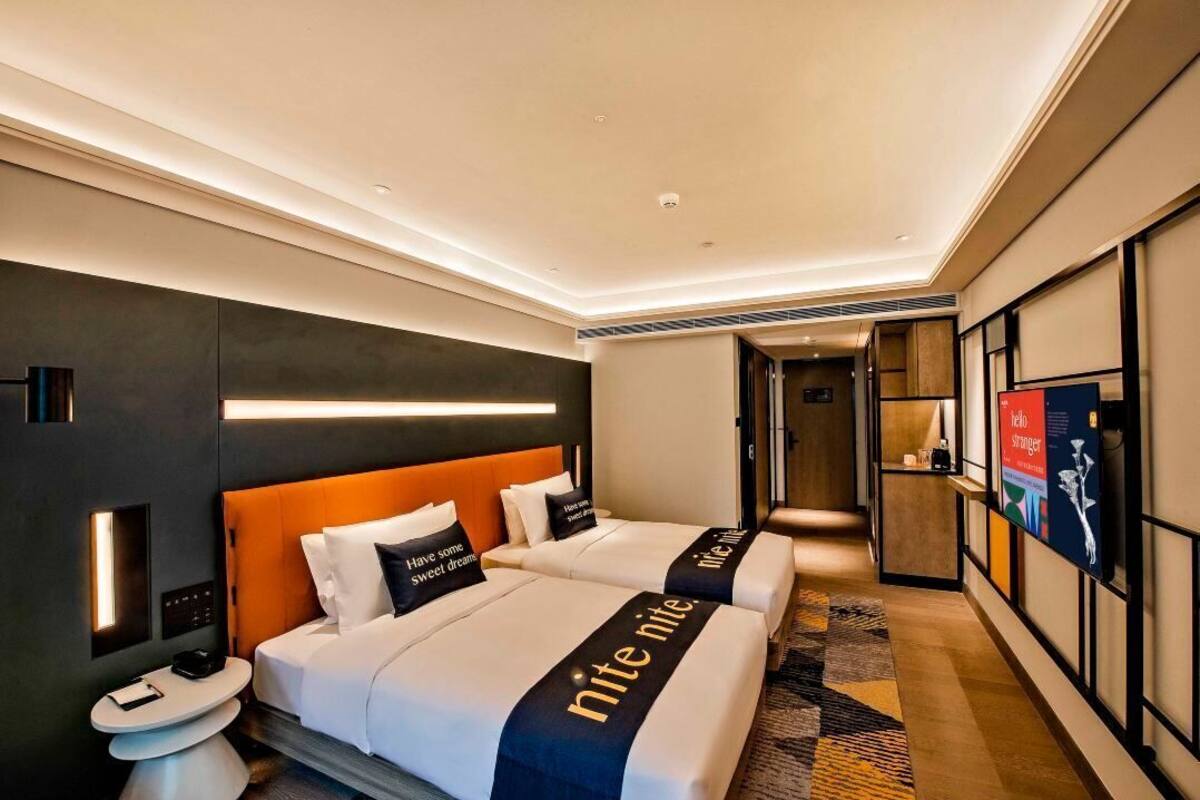 Ein Hotelzimmer mit zwei Betten, modernem Design und Blick auf den Flur.