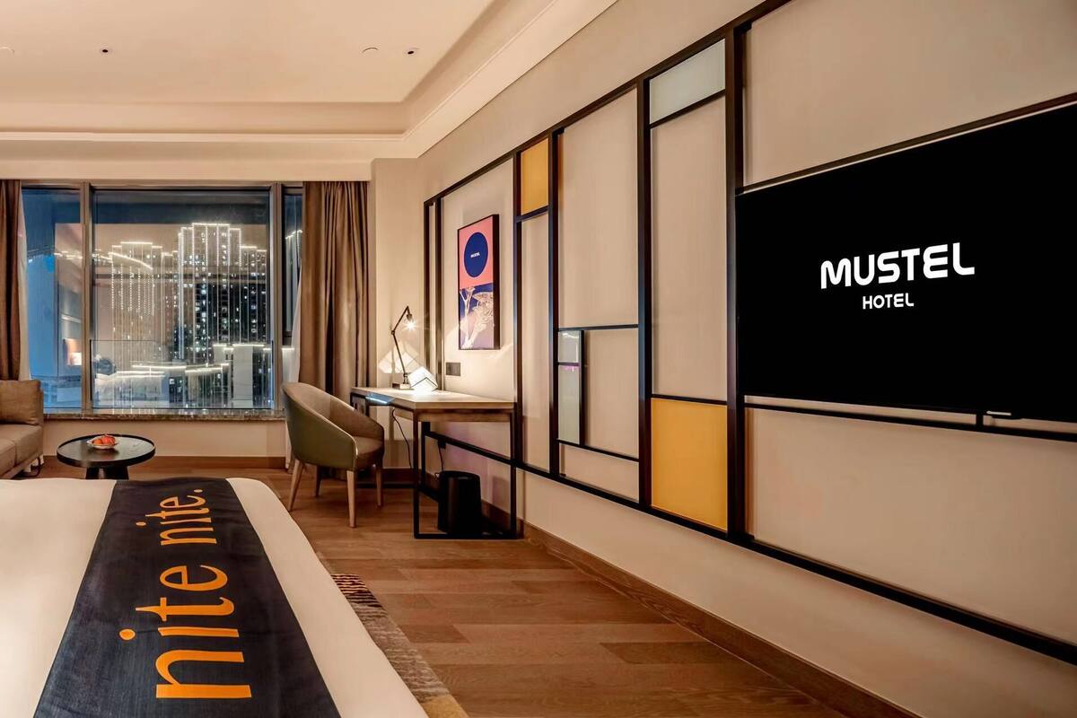 Ein modernes Hotelzimmer mit einem großen Bett, einem Schreibtisch und Blick auf die Stadt.