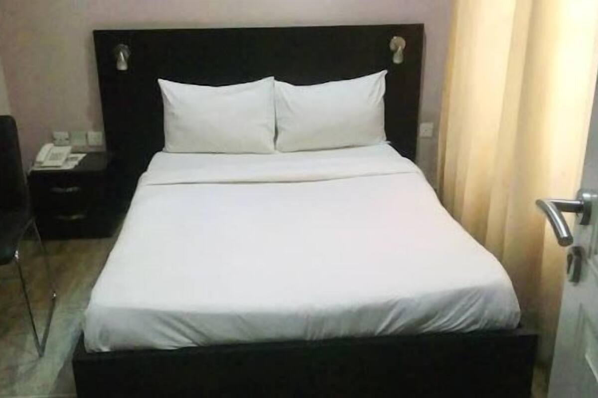 En pænt redt seng med hvide sengetøj i et hotelværelse.