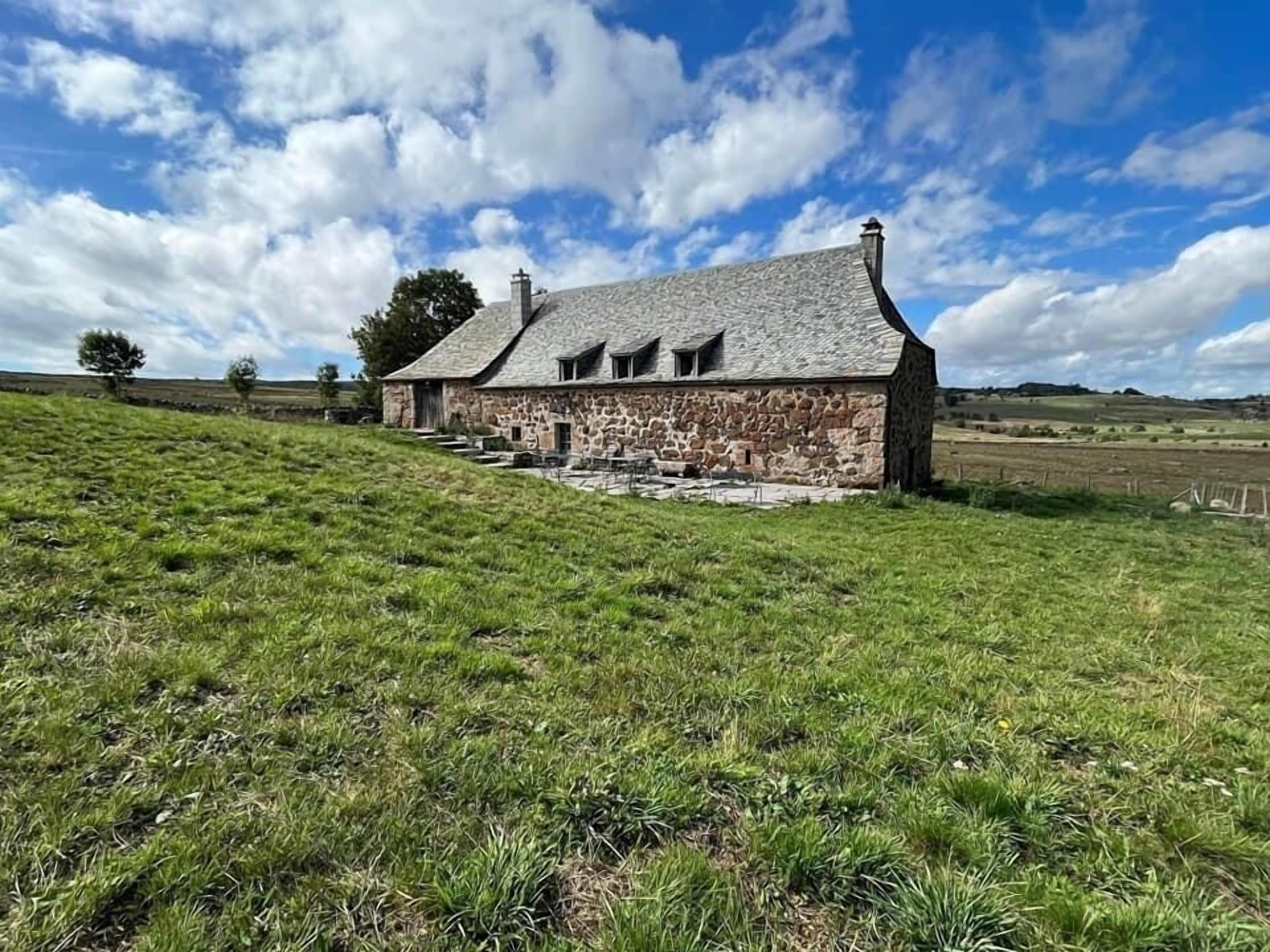 A stone house with a sloped roof and a stone staircase leading to the entrance.