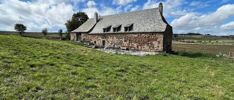 A stone house with a sloped roof and a stone staircase leading to the entrance.