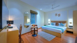 A hotel room with a bed, bedside tables, a desk, a chair, a mirror, a ceiling fan, and a window. - Nest By TreeHouse Stamp Amritsar (Amritsar)