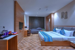 A hotel room with a bed, a desk, a television, and a large window with curtains. - Nest By TreeHouse Stamp Amritsar (Amritsar)