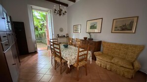 A dining area with a table set for four, wooden chairs, a sofa, and a chandelier. - Holiday Home in Meina (Meina)