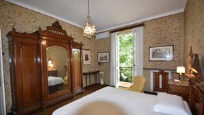 A bedroom with a large bed, wooden wardrobe, and a chandelier. - Holiday Home in Meina (Meina)